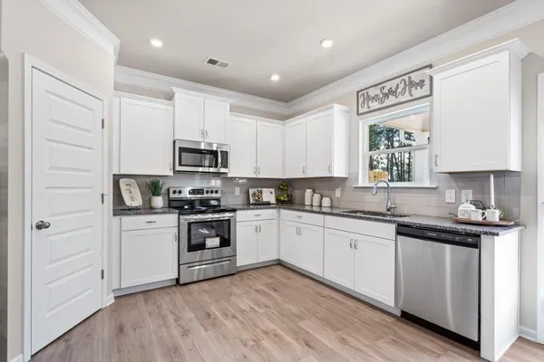 a kitchen with granite countertop white cabinets and stainless steel appliances
