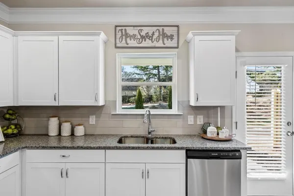 a kitchen with granite countertop white cabinets and window