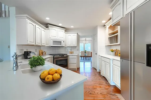 a kitchen with stainless steel appliances a stove a sink and white cabinets