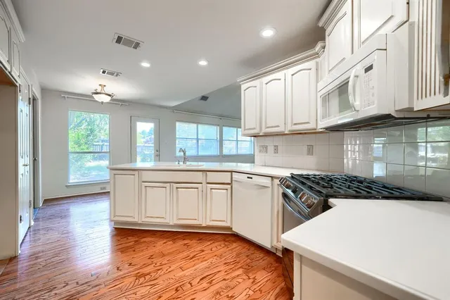 a kitchen with stainless steel appliances granite countertop a stove a sink and white cabinets