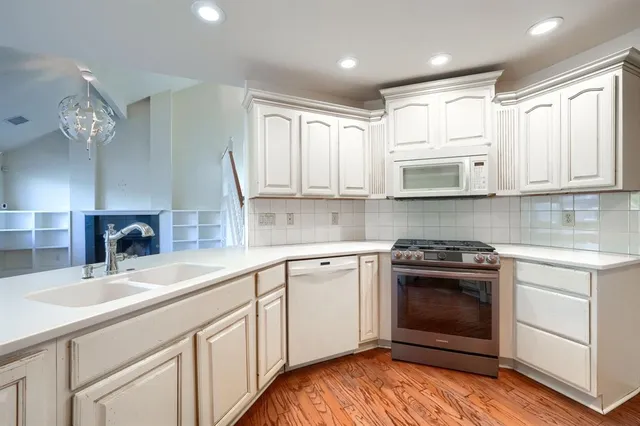 a kitchen with stainless steel appliances granite countertop a sink and cabinets with wooden floor