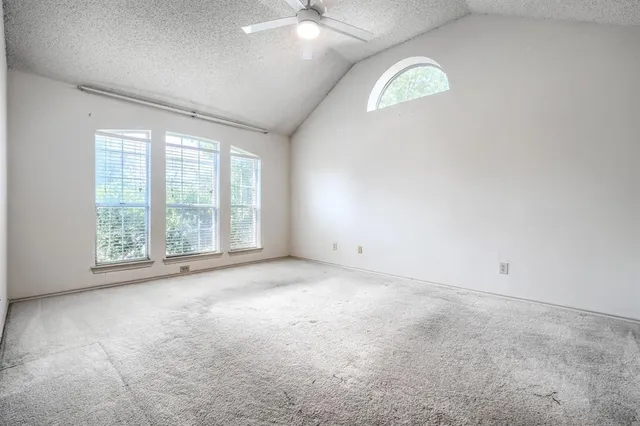 an empty room with a ceiling fan and window