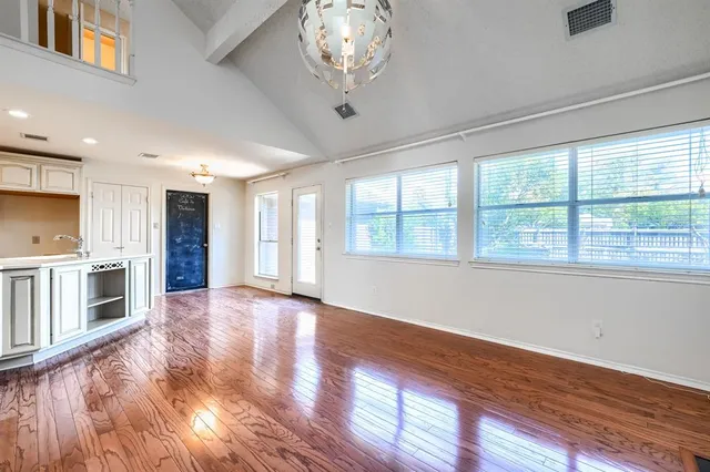 a view of an empty room with a window and wooden floor
