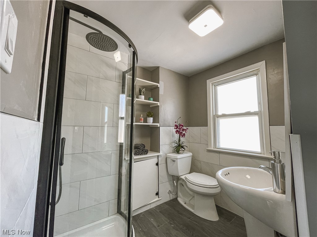 24709 Emery Road Warrensville Heights, OH 44128 - Photo 19 of 34 Bathroom with hardwood / wood-style flooring, toilet, a shower with door, tile walls, and sink