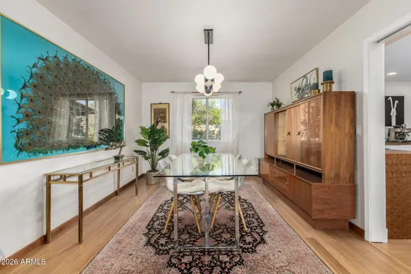 a dining room with wooden floor a chandelier a wooden table and chairs