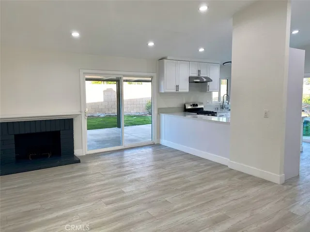 a kitchen with stainless steel appliances granite countertop a refrigerator a sink dishwasher a stove and white countertops with wooden floor