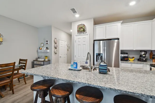 a kitchen with granite countertop a table chairs stove and refrigerator