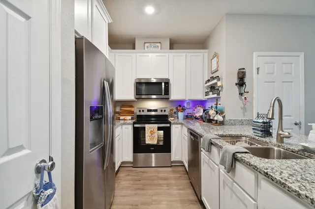 a kitchen with granite countertop a refrigerator stove and sink