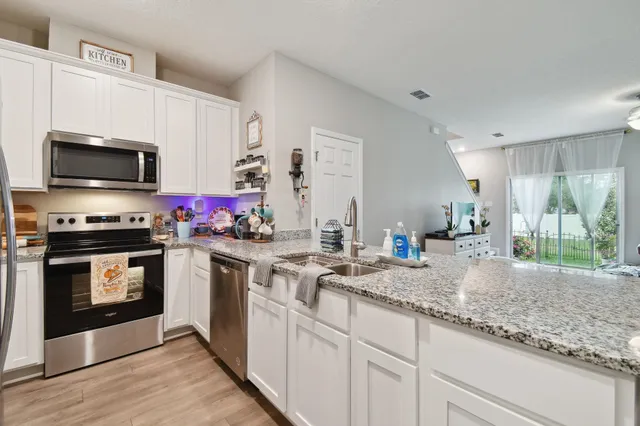 a kitchen with granite countertop a sink cabinets and stainless steel appliances