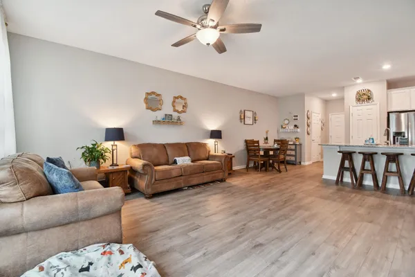 a living room with furniture and a dining table with wooden floor