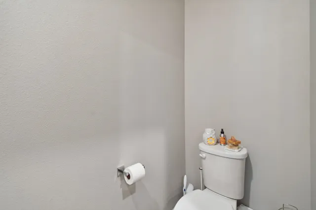 a white toilet sitting next to a white wall