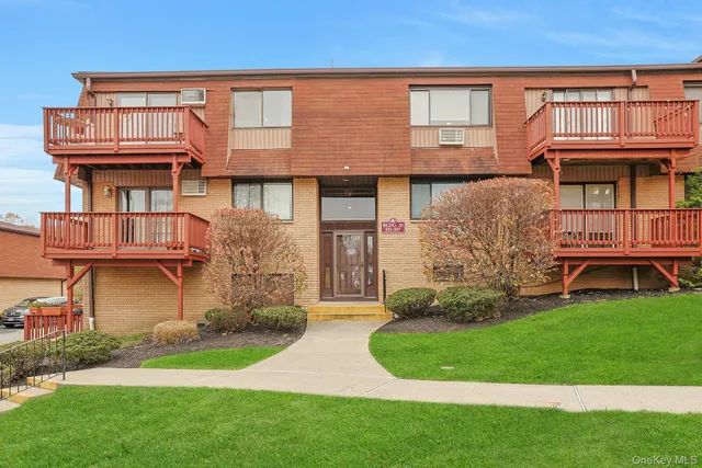 a view of a brick house with a yard and plants
