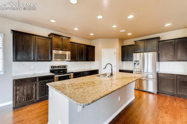 a large kitchen with stainless steel appliances granite countertop a large counter top and a stove top oven
