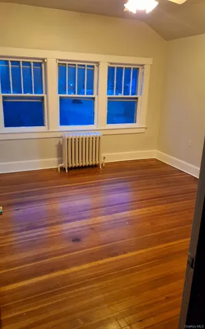 a view of an empty room with wooden floor and windows