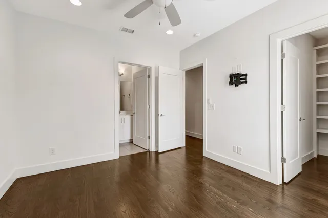an empty room with wooden floor and ceiling fan
