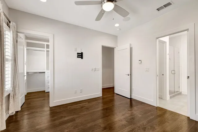 an empty room with wooden floor fan and windows