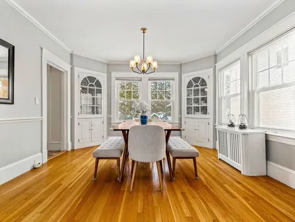 a dining room with wooden floor a chandelier a glass table and chairs
