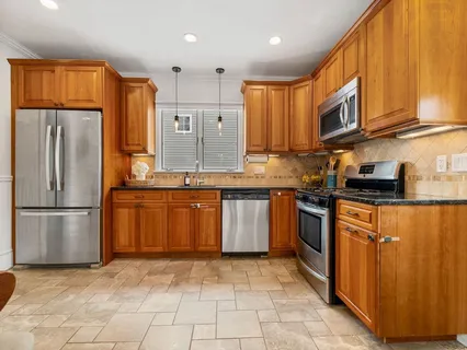 a kitchen with stainless steel appliances granite countertop a refrigerator a stove a sink and a microwave