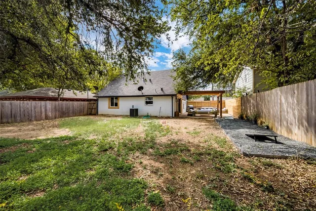 a view of a backyard with a large tree and wooden fence