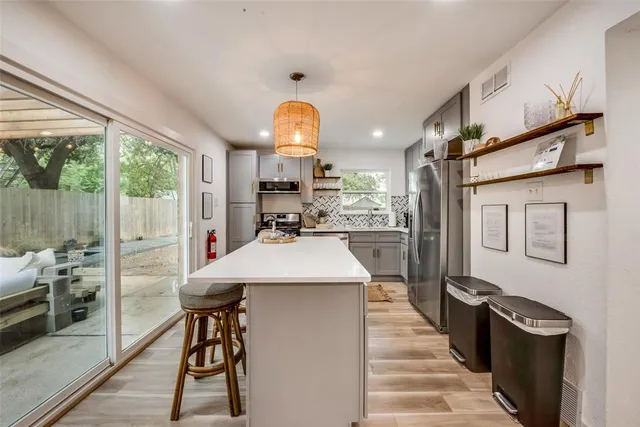 a kitchen with stainless steel appliances kitchen island a table chairs in it and wooden floors