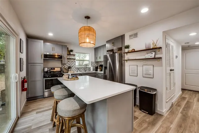 a kitchen with stainless steel appliances a dining table chairs refrigerator and stove