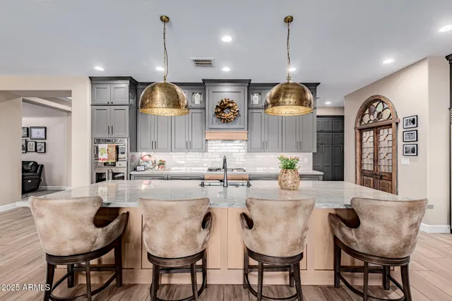 a dining hall with stainless steel appliances kitchen island granite countertop a table chairs and a wooden floor