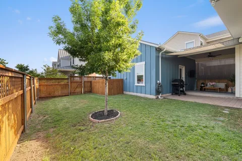 a view of a house with backyard and a tree