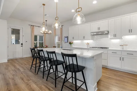 a kitchen with kitchen island a dining table chairs and white cabinets