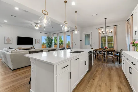 a open kitchen with stainless steel appliances granite countertop a stove top oven a sink dishwasher a dining table and chairs with wooden floor