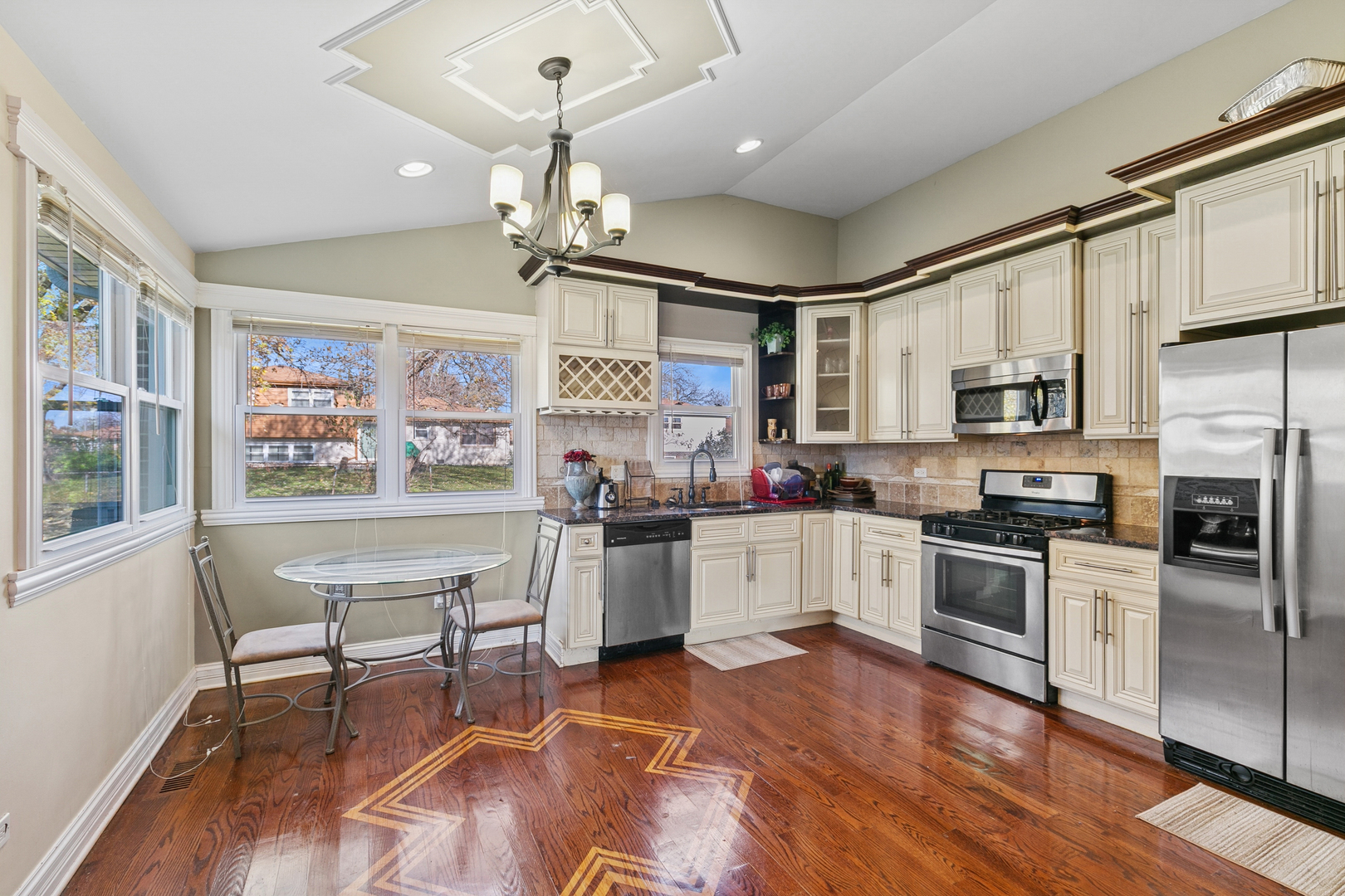 6306 Beaver Dam Road Matteson, IL 60443 - Photo 5 of 20 a kitchen with stainless steel appliances granite countertop a stove top oven a sink dishwasher a dining table and chairs with wooden floor