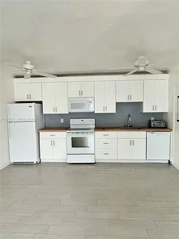 a kitchen with granite countertop white cabinets and white stainless steel appliances