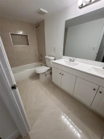 a bathroom with a granite countertop sink mirror vanity and toilet