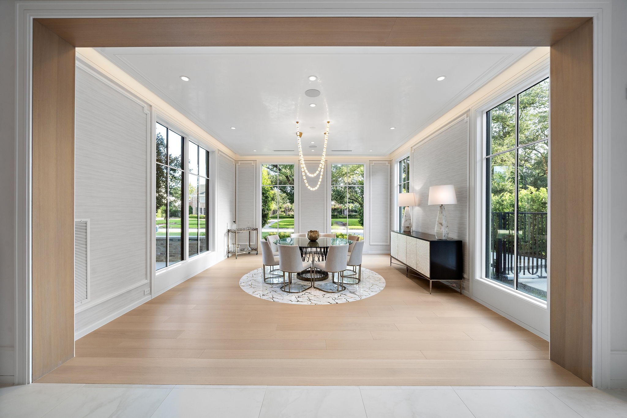 3649 Chevy Chase Drive Houston, TX 77019 - Photo 5 of 50 Venetian plaster ceiling, cove lighting, and wood flooring inset with custom marble design define the space with sophistication, while Holly Hunt wallpaper adds refined texture. Floor-to-ceiling windows frame front garden views.