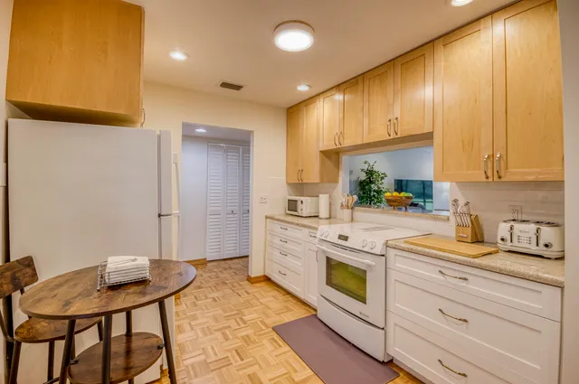 a kitchen with stainless steel appliances kitchen island granite countertop a stove a sink and a refrigerator with wooden cabinets