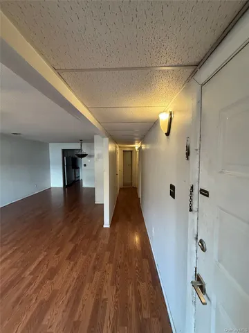 a view of a hallway with wooden floor and a bathroom