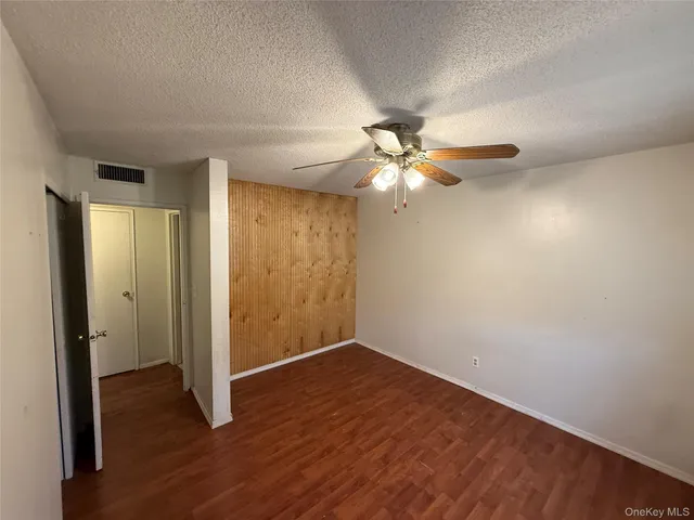 an empty room with wooden floor and fan