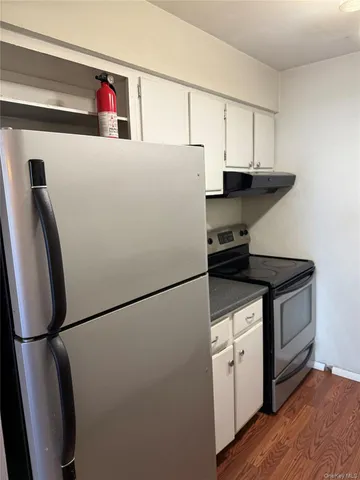 a kitchen with metallic refrigerator and white cabinets