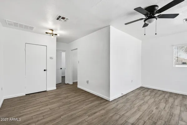an empty room with wooden floor a ceiling fan and closet