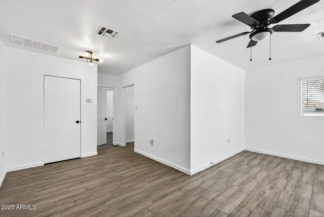 an empty room with wooden floor a ceiling fan and closet