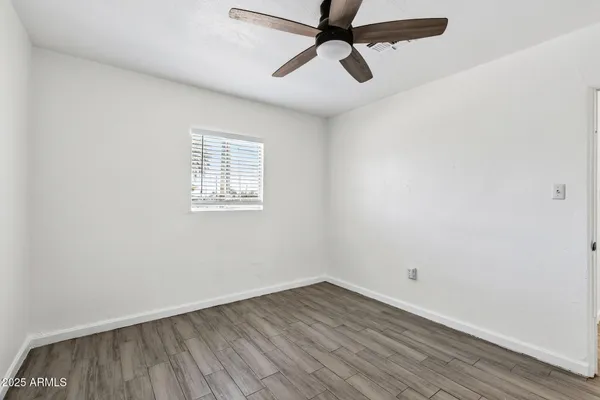 an empty room with a window and a ceiling fan