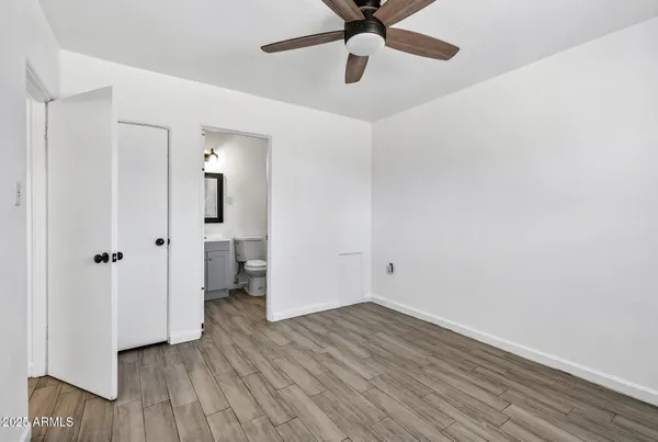 an empty room with wooden floor and a ceiling fan