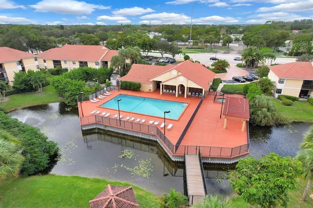 a view of a white house with a big yard and potted plants