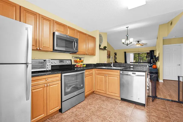 a kitchen with stainless steel appliances granite countertop a stove a sink dishwasher and a refrigerator