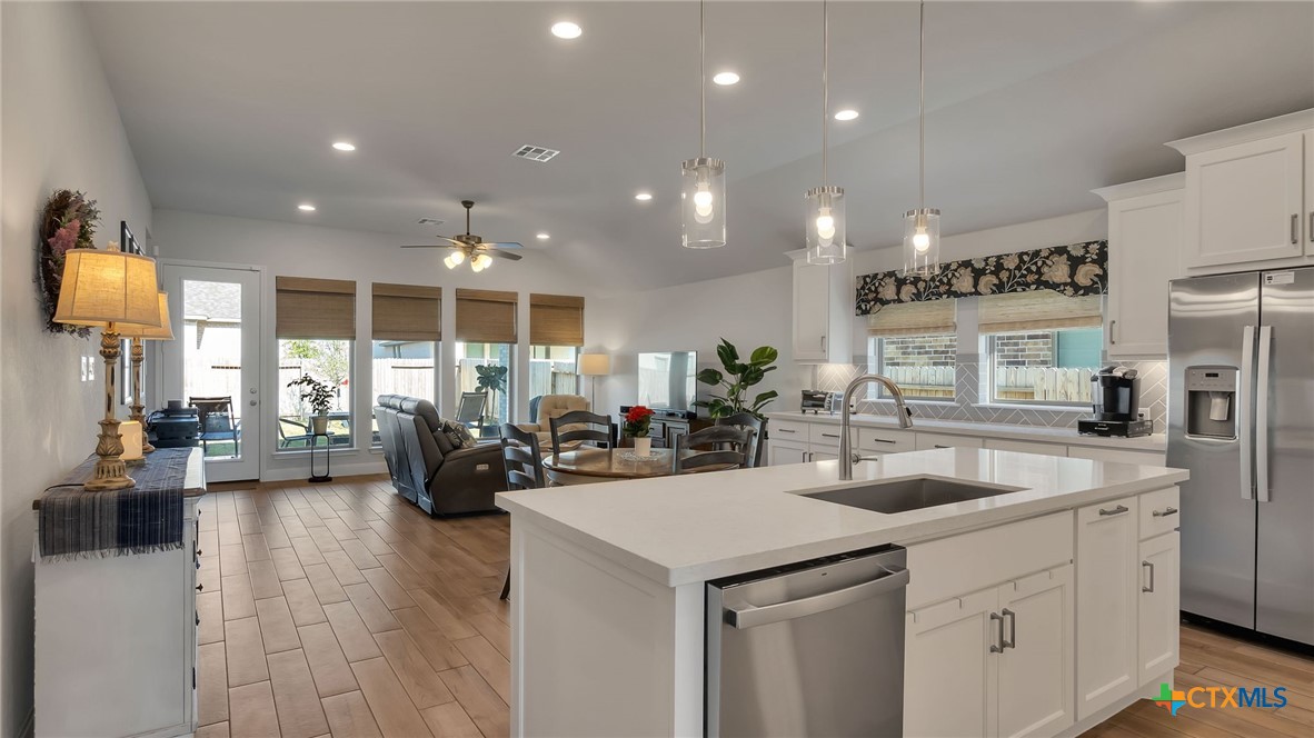 1816 Field Brook Seguin, TX 78155 - Photo 7 of 32 a kitchen with sink refrigerator and couches with wooden floor