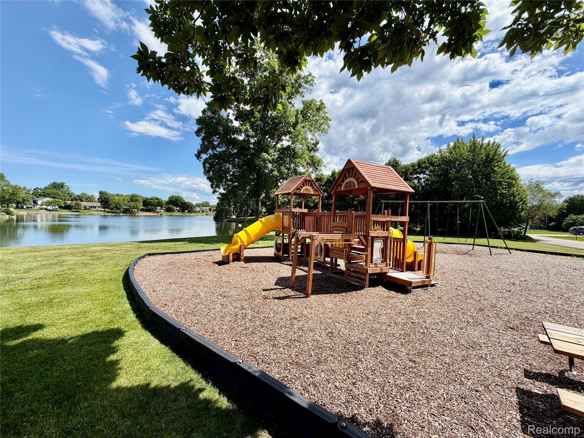 22533 Winfield Road Novi, MI 48375 - Photo 39 of 43 Community playground featuring a multi-level wooden play structure, two yellow slides, and a swing set