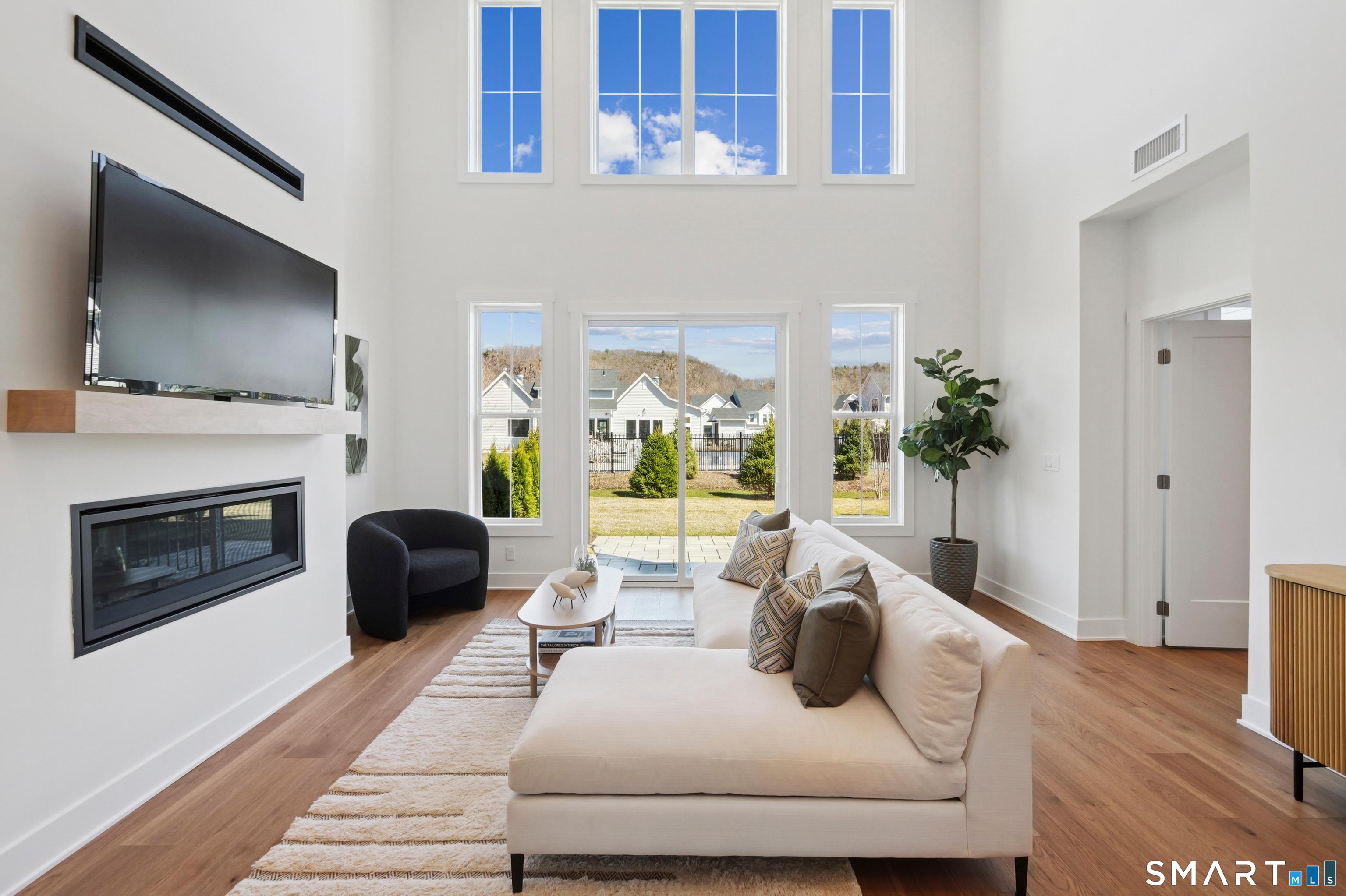 5 Edgewood Way, Unit 25 Woodbridge, CT 06525 - Photo 2 of 8 staged model of Silliman Modern Farmhouse showing great room with linear fireplace and slider to the patio. Home also features two story windows and 17 foot ceiling height.