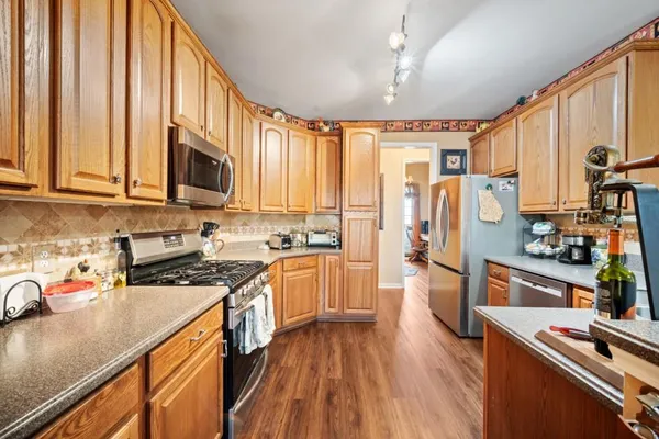 a kitchen with stainless steel appliances granite countertop a stove top oven a sink dishwasher a refrigerator and cabinets with wooden floor