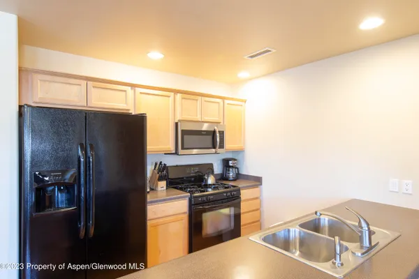 a kitchen with stainless steel appliances granite countertop a refrigerator a stove and a sink with wooden floor