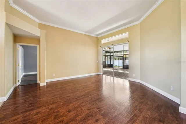 a view of an empty room with window and wooden floor