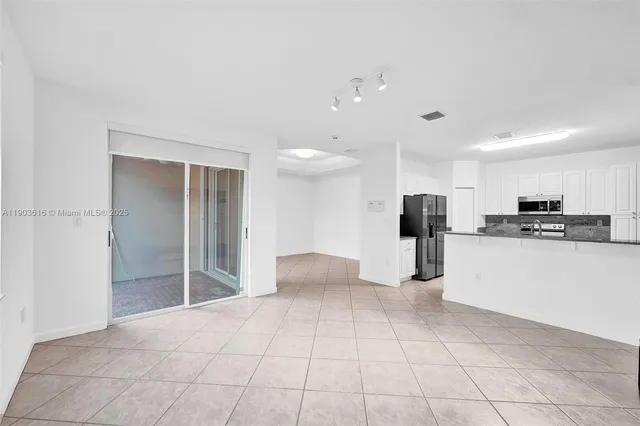 a view of a kitchen with refrigerator and white cabinets
